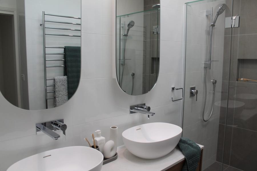 Modern bathroom vanity with twin basins, mirrors and glass shower