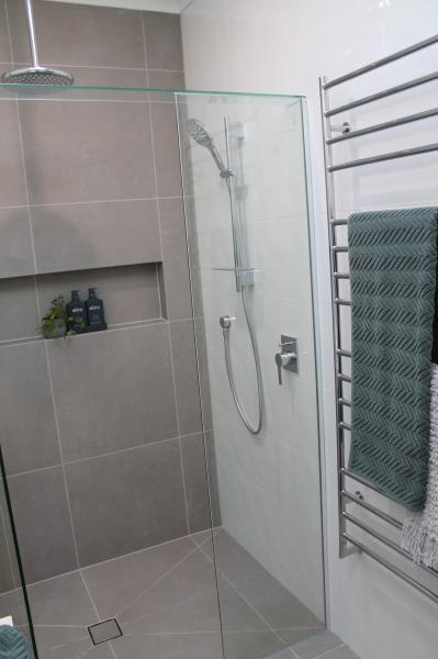 Frameless glass shower with recessed niche, grey wall tiles and chrome heated towel rail