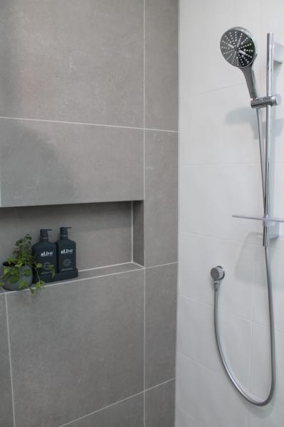 Grey tiled shower with recessed niche and handheld chrome shower