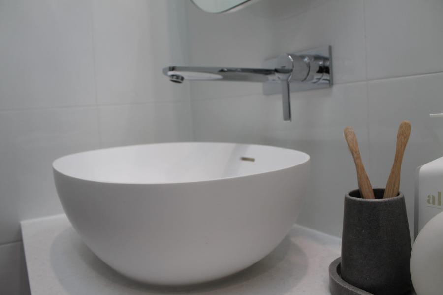 White round vessel basin with chrome wall-mounted tap on a modern bathroom vanity