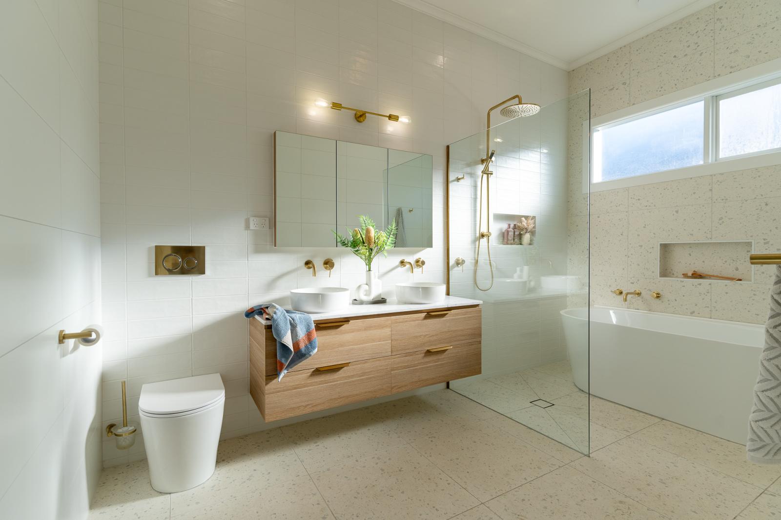 Modern bathroom with timber vanity, gold tapware and marble tiles