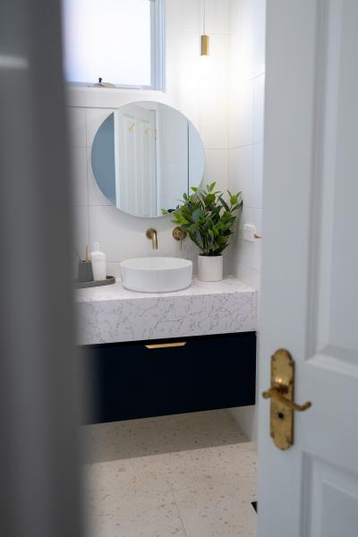 Modern bathroom vanity with round mirror, vessel basin and dark cabinetry