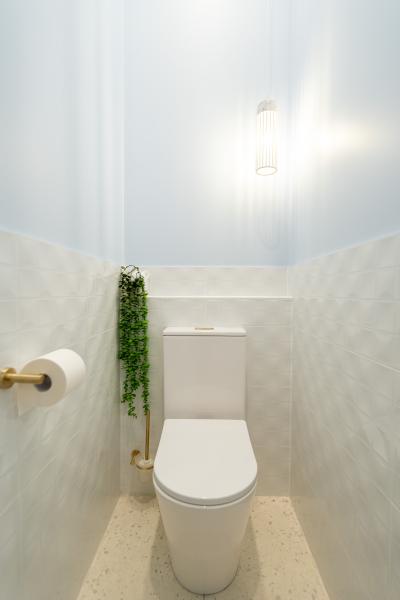Modern white toilet in a narrow powder room with pale patterned wall tiles