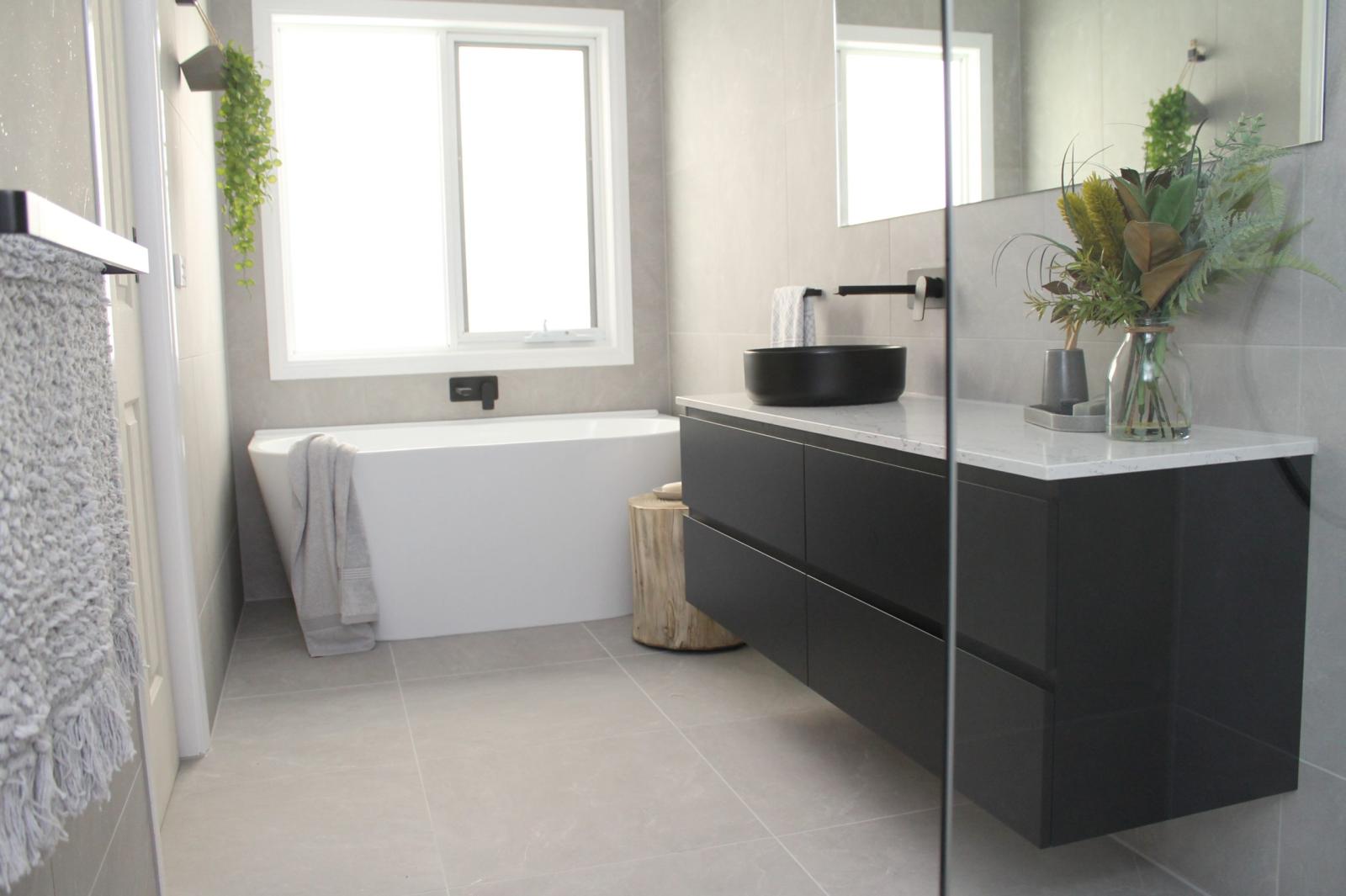 Modern bathroom with black vanity, freestanding bath, white tiles