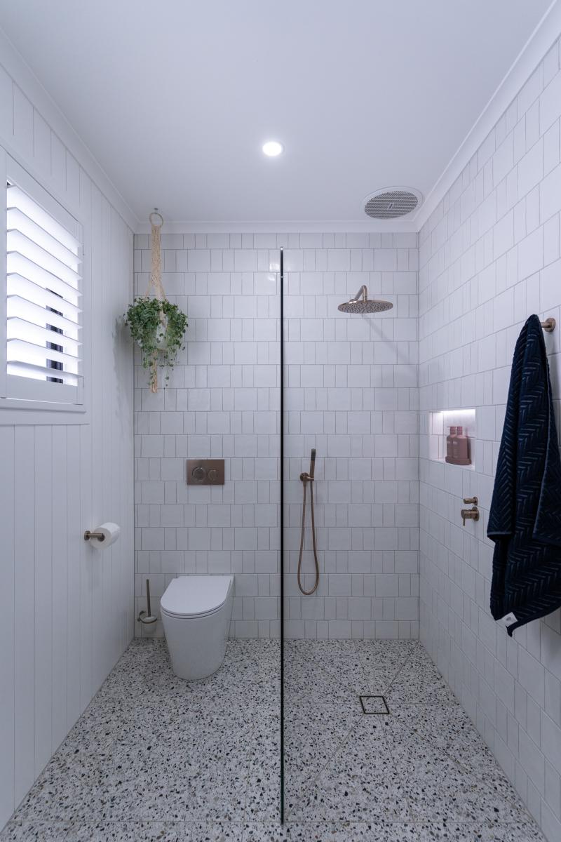 Modern bathroom with white tiles, shower, and toilet