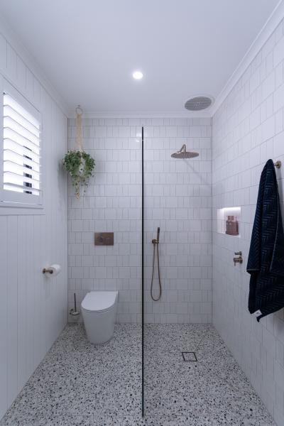 Modern bathroom with white tiles, shower, and toilet