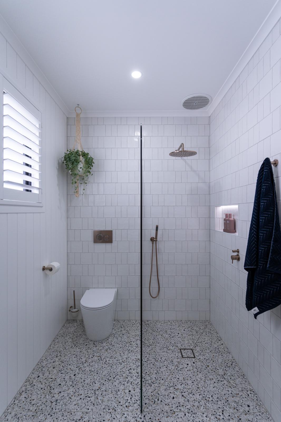 Modern bathroom with white tiles, shower, and toilet