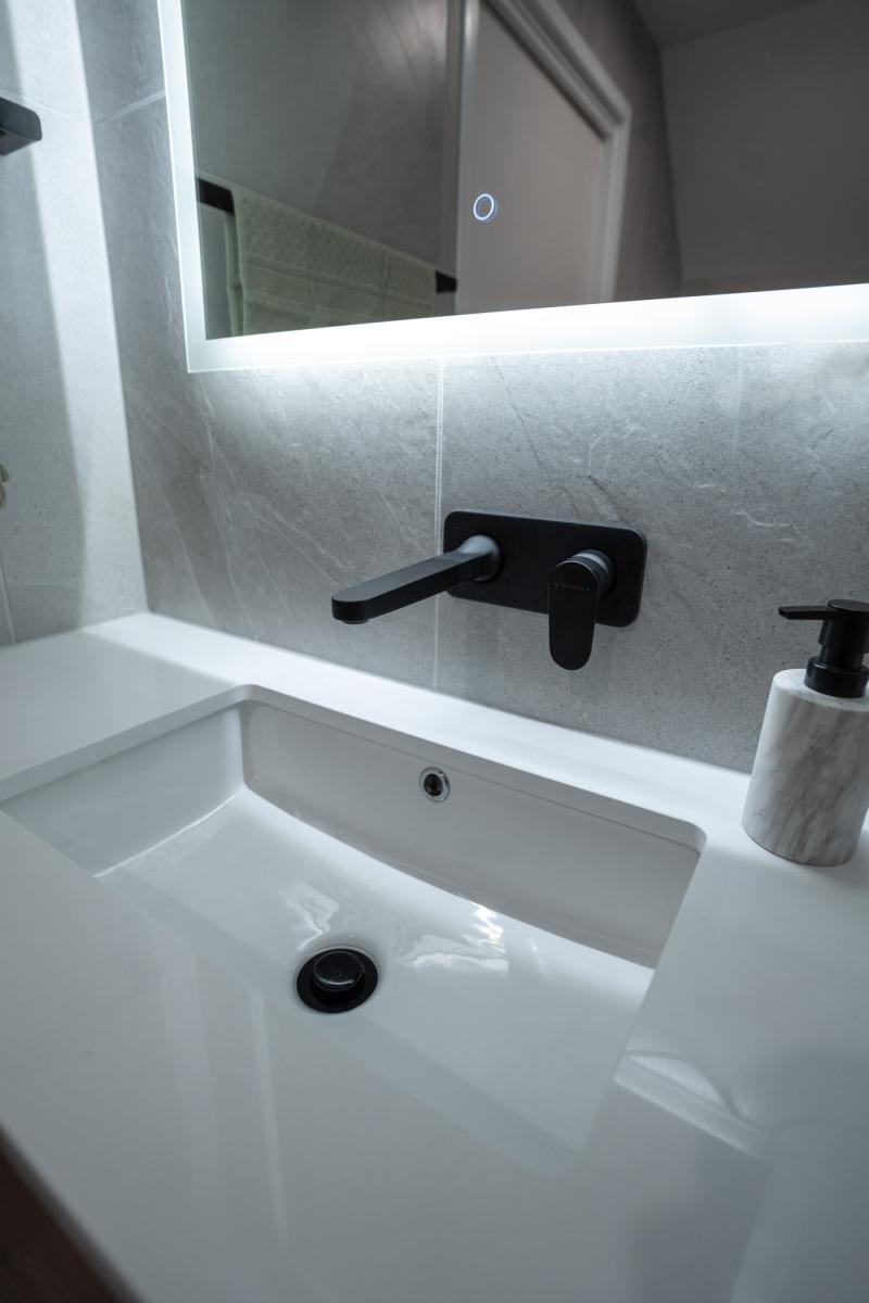 Modern bathroom vanity with black wall-mounted tap and LED mirror