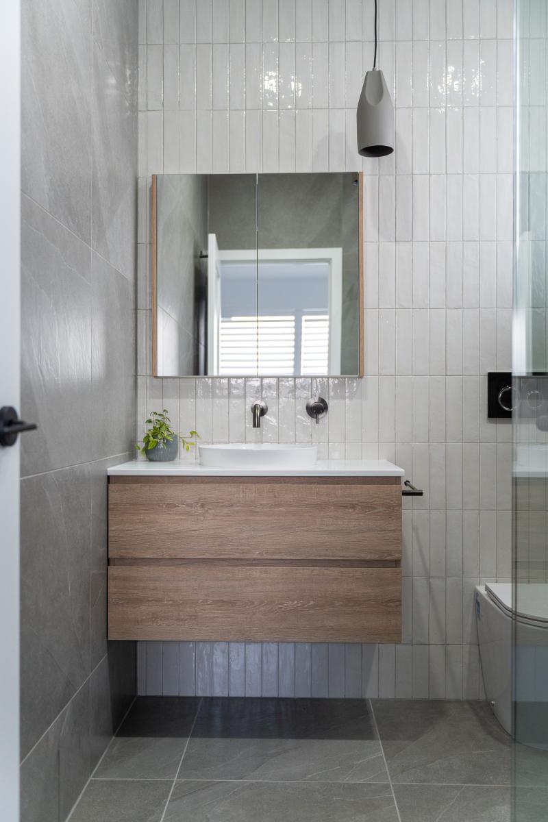 Modern bathroom vanity with timber cabinetry and grey tiles