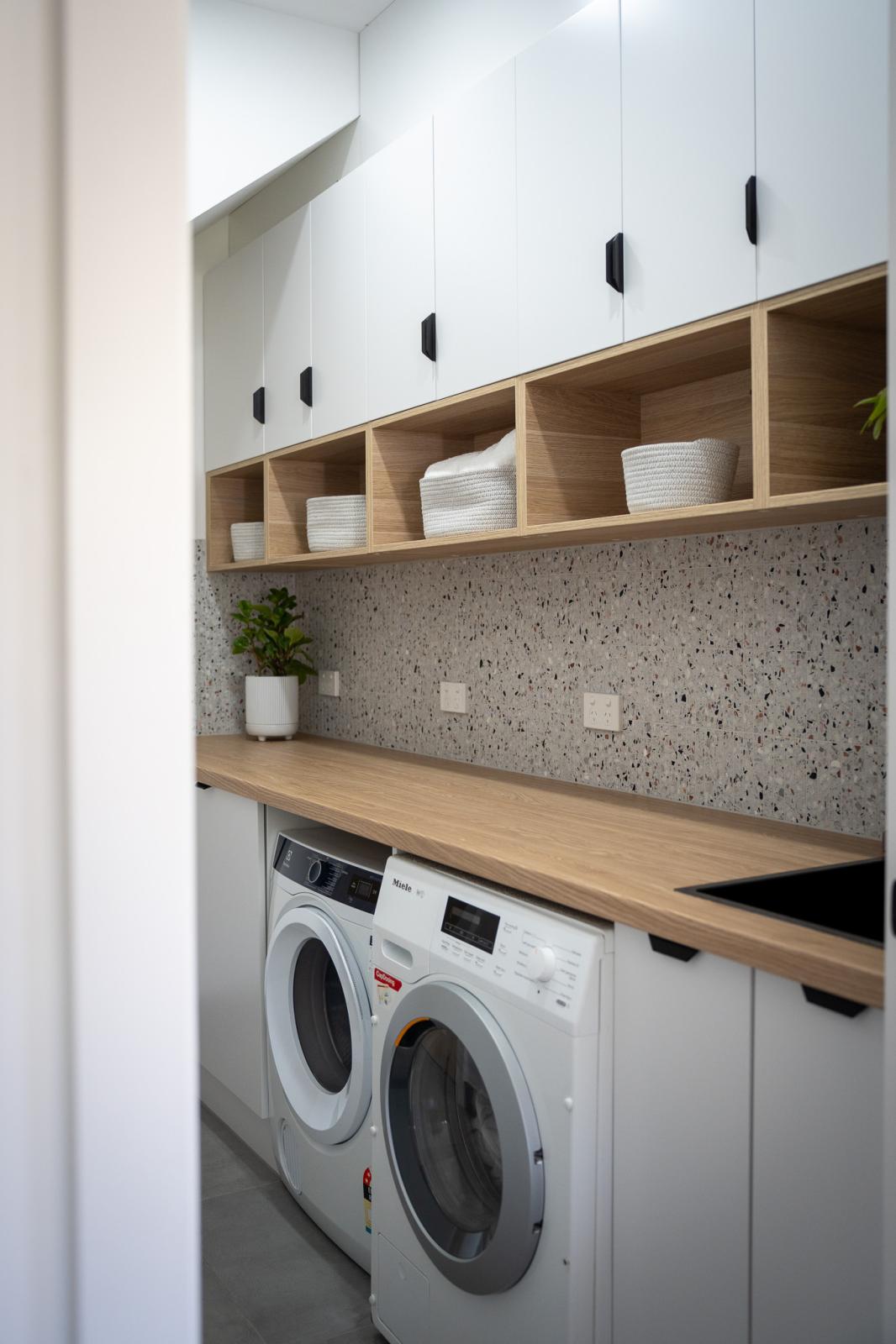 Modern laundry room with white cabinetry and timber benchtop