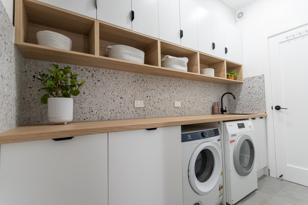 Modern laundry room with dual washing machines and timber cabinetry