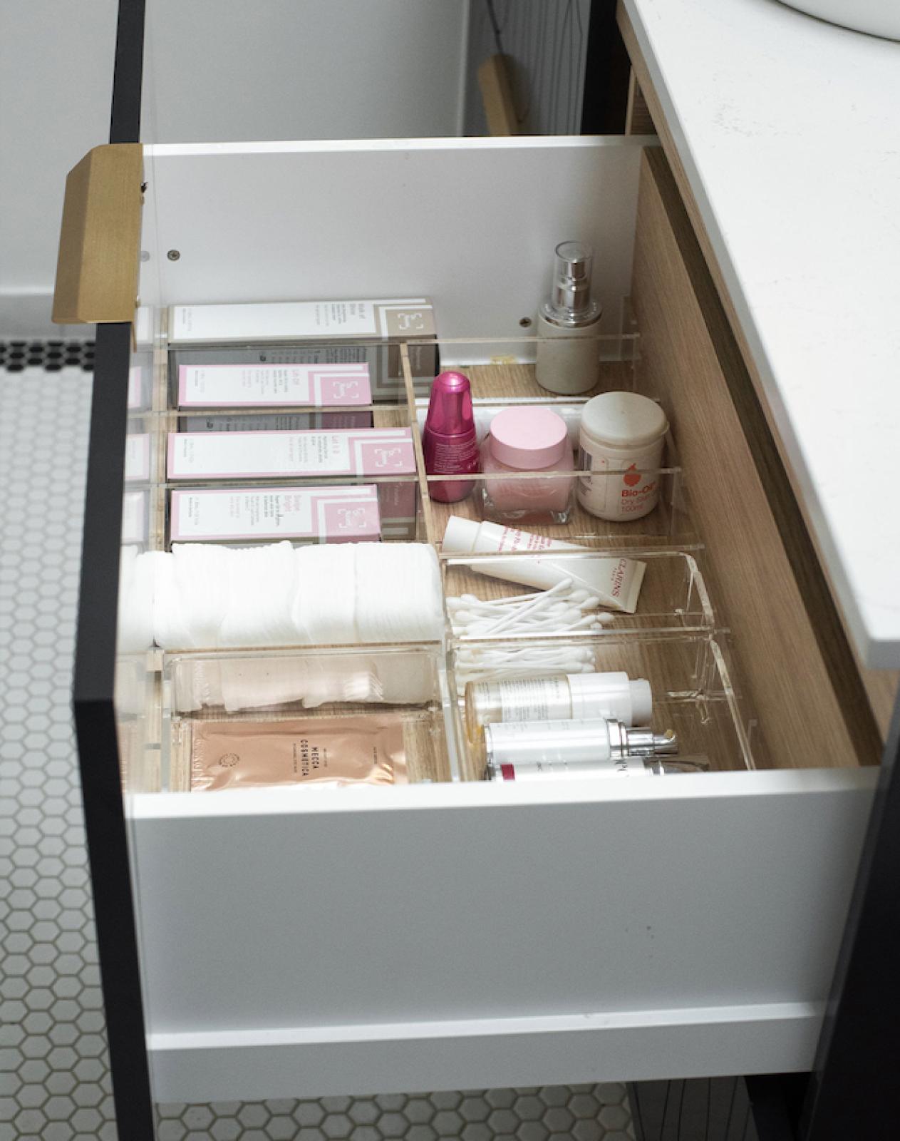 Organised bathroom vanity drawer with acrylic trays storing cosmetics, cotton pads and toiletries