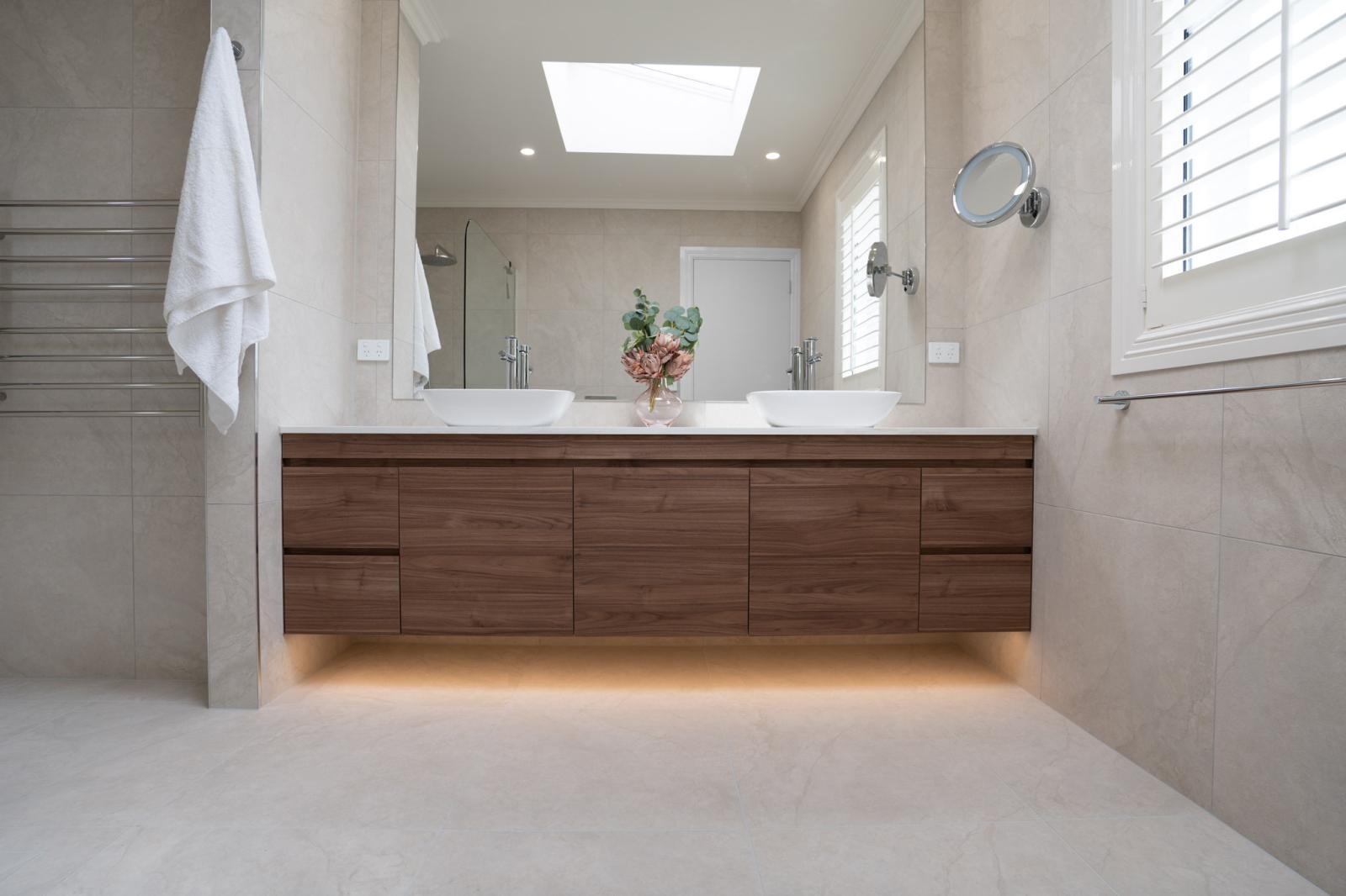 Modern bathroom with large timber vanity, dual basins, and underlit cabinetry
