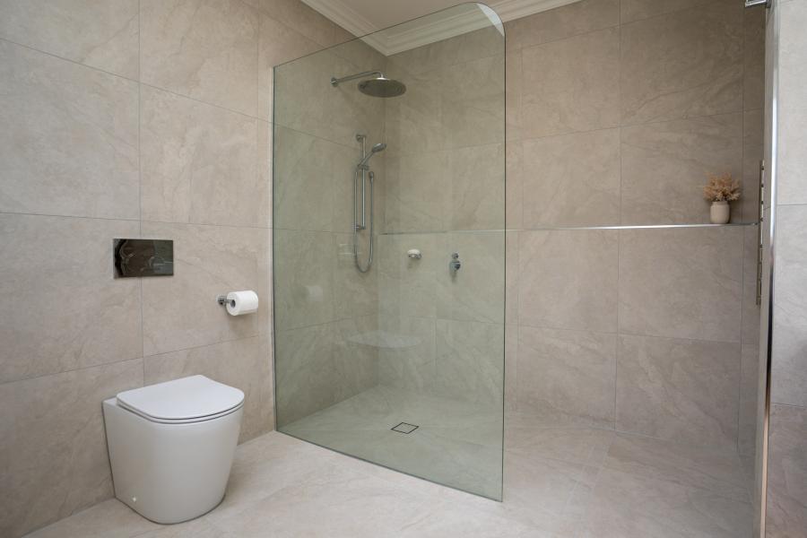 Modern ensuite bathroom with walk-in shower, rimless toilet, and neutral tile finishes