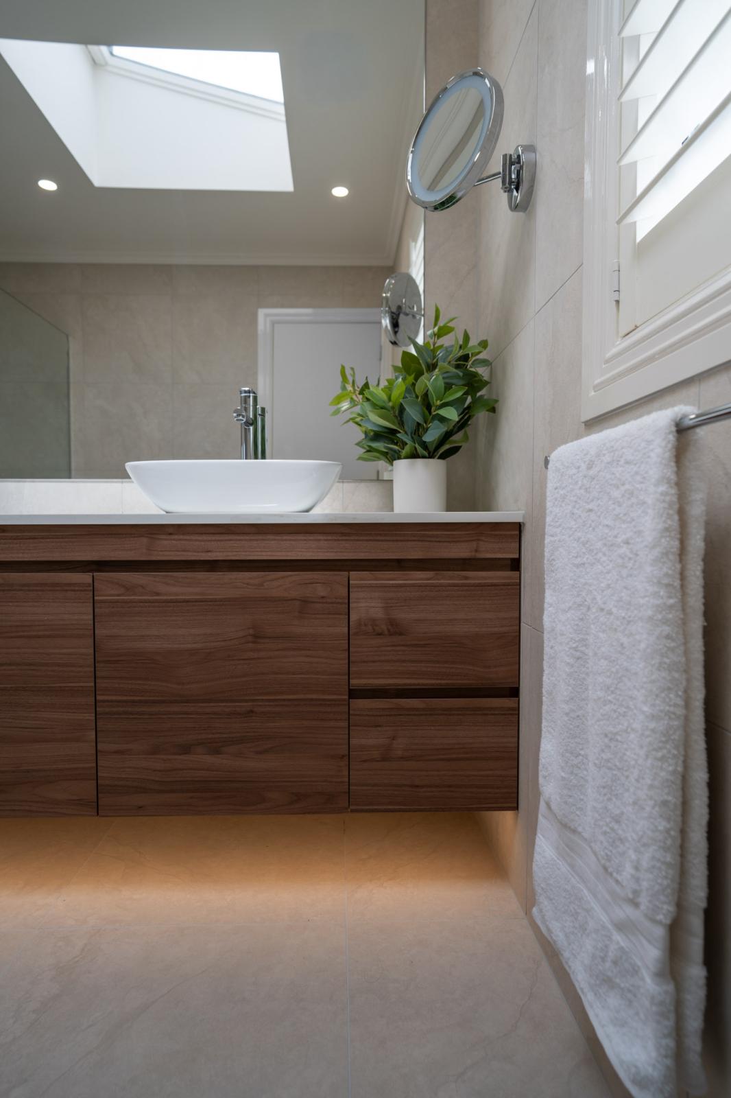 Modern bathroom vanity with timber cabinetry, white basin, and skylight