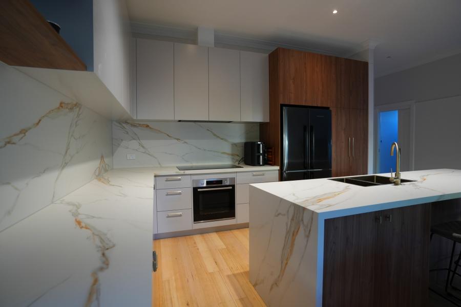 Modern kitchen with marble island, white cabinetry and timber finishes