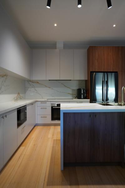 Modern kitchen with white cabinetry, timber flooring and dark island bench