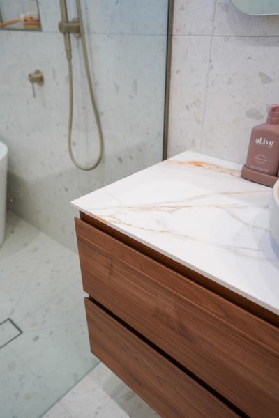 Modern bathroom vanity with stone benchtop beside walk-in shower