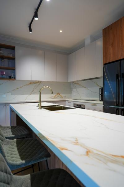 Modern kitchen with white marble island, timber cabinetry and black fridge