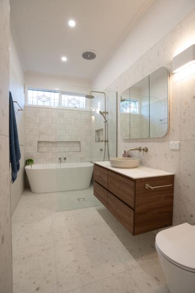 Modern white bathroom with freestanding bath, timber vanity and frameless shower screen