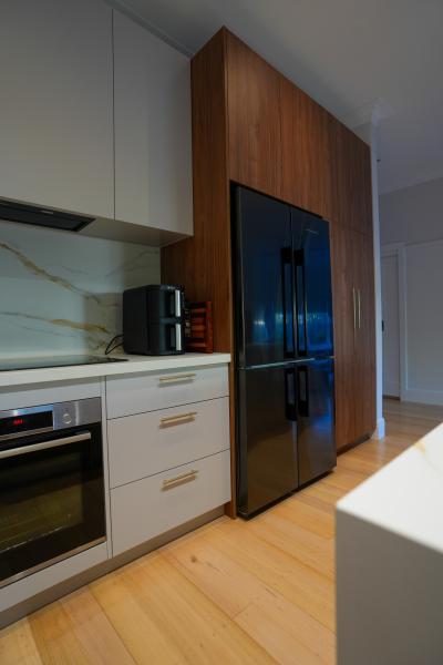 Modern kitchen with integrated oven, white cabinetry and black double-door fridge