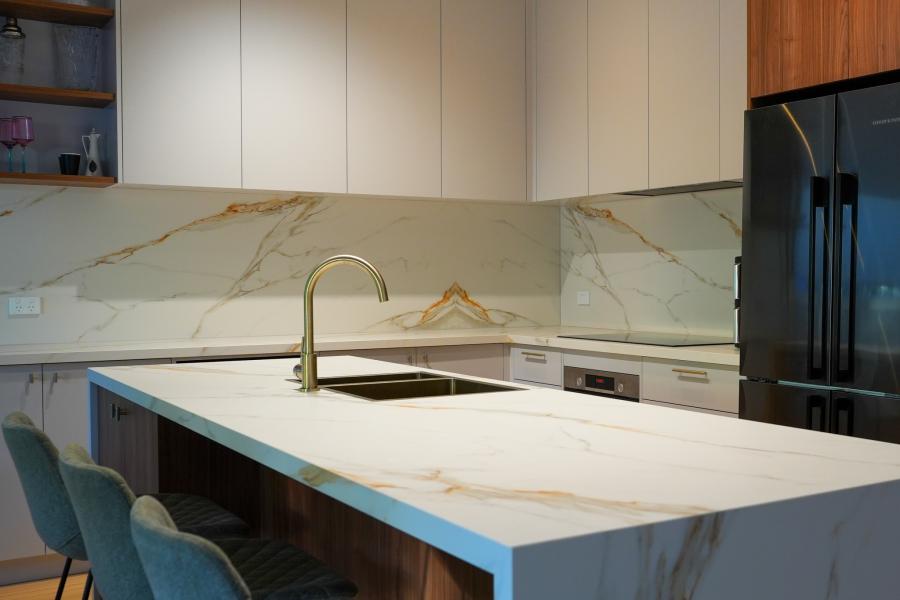 Modern kitchen with marble island, brass tapware and white cabinetry