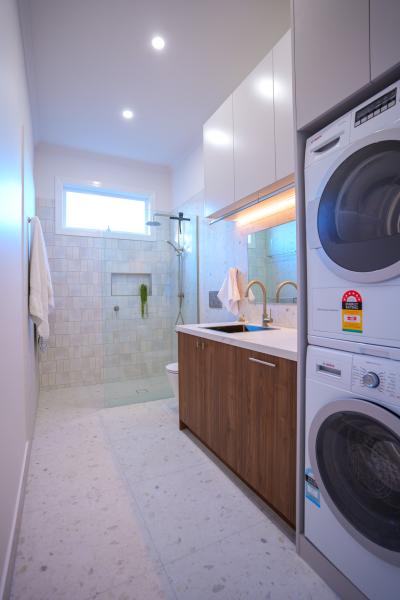 Modern bathroom laundry combo with timber vanity, stacked washer dryer and walk-in shower