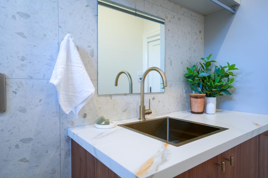 Modern laundry sink with brass tap, stone benchtop and mirror cabinet